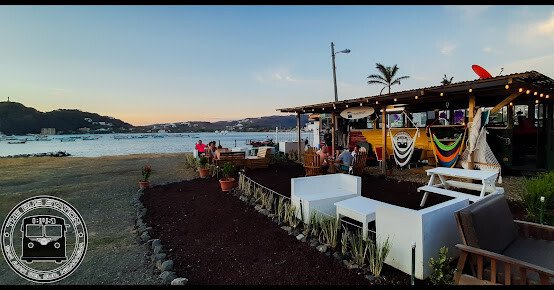 The BUS Station's vibrant bar area with patrons enjoying drinks and live music in San Juan del Sur, Nicaragua