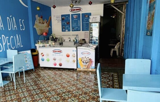 Eskimo Ice Cream shop in San Juan del Sur with bright sign and beachgoers passing by.