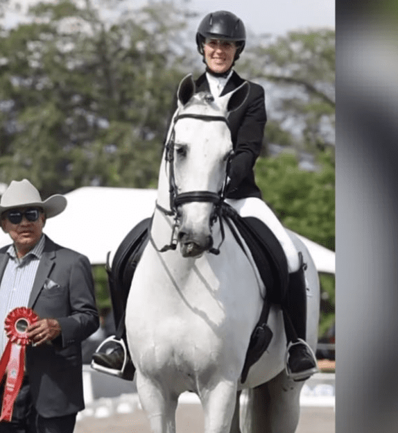 Marie horse riding lessons: image of Marie on a white horse at a competition winning a badge